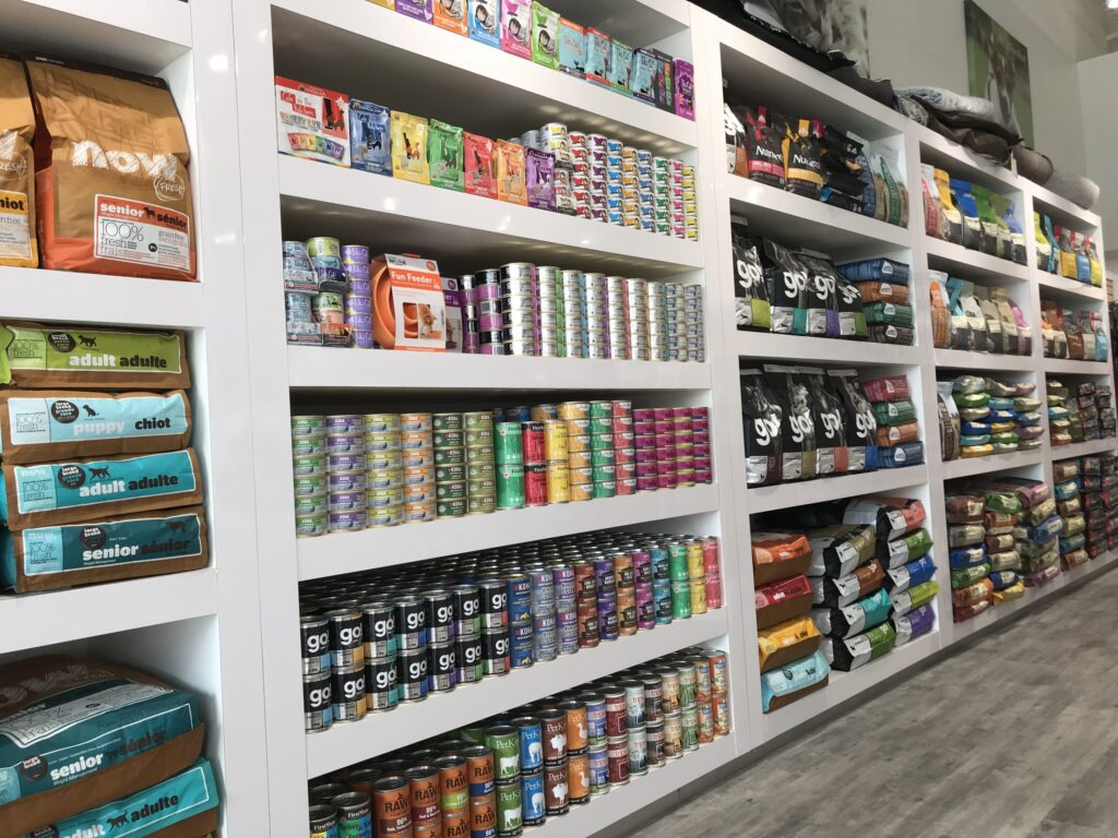 The store shelves with canned dog food and wet cat food, as well as bags of dry dog food and dry cat food, at the Bone & Biscuit Heritage Valley Edmonton pet store.