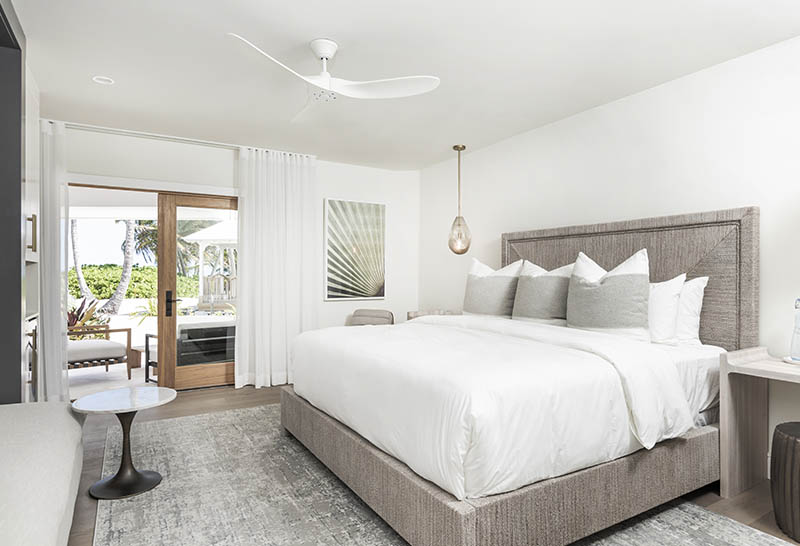 Elegant bedroom at Caerula Mar Club, South Andros, Bahamas with luxe bedding, patio access, and palm views at this luxury resort.