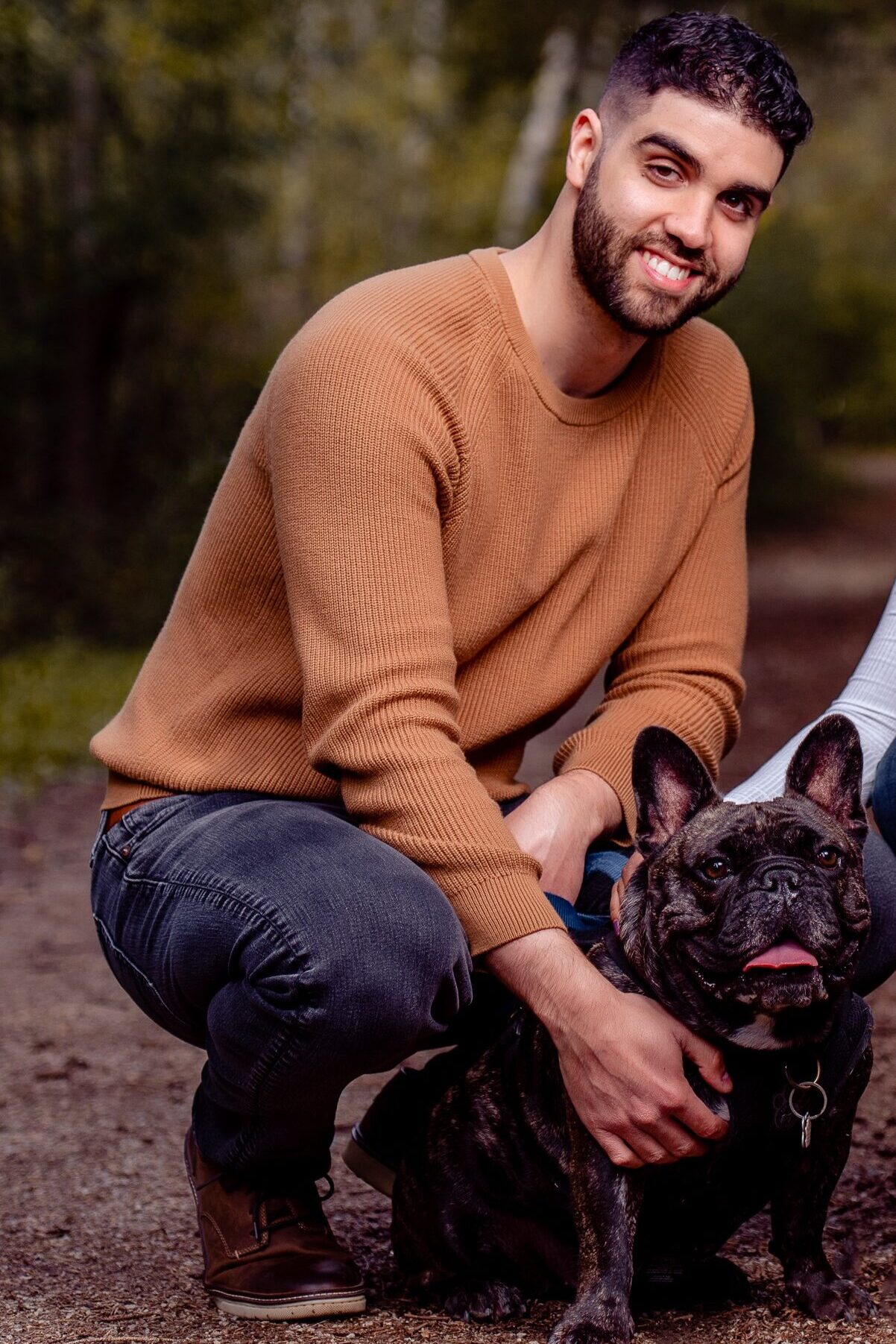 Christopher, one of the new store owners of the new Bone & Biscuit Yonge Sheppard location in North York Ontario, crouches next to his bulldog named Gordy.