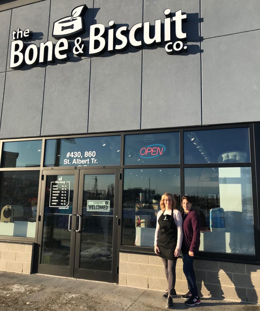 Tara and her manager standing in front of the Bone & Biscuit Jensen Lake location in St. Albert, Tara's first Bone & Biscuit store.