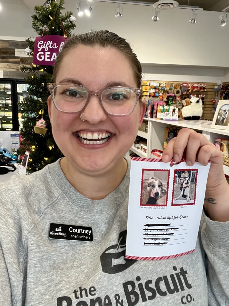 Courtney, the owner of the new Bone & Biscuit Garneau in Edmonton, smiles while holding up a dog's wishlist for the GEARS initiative, a rescue association helping animals in Edmonton.